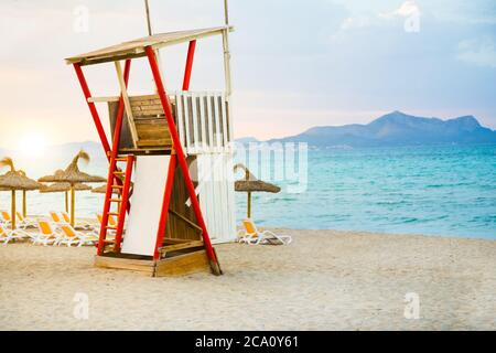 Lifeguard hut standing at Mediterranean sea at sunset with mountain landscape Stock Photo