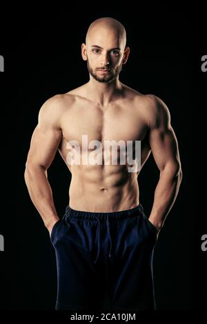 Athletic man with hands in pocket look straight at camera while show his well trained abs Stock Photo