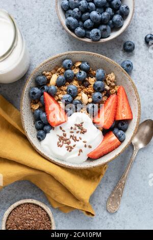 Granola bowl with berries and yogurt on concrete background. Healthy breakfast food top view vertical orientation Stock Photo
