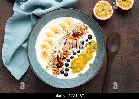 Breakfast yogurt bowl with mango and granola on a wooden table