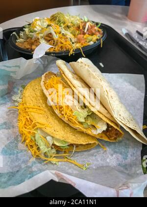 mexican fastfood hard and soft taco with cheese at restaurant table served for dinner as full meal wraped in paper should look tasty Stock Photo