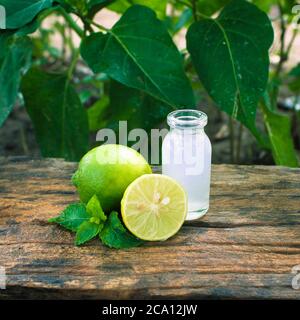 Half cut lemon and a small glass jar full of lemon juice on a wooden table closeup Stock Photo