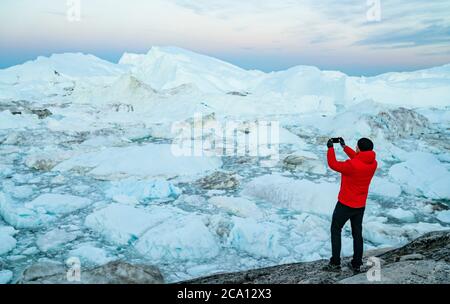 Travel in landscape with icebergs. Greenland man taking photo with phone of amazing Greenland icefjord in Ilulissat Stock Photo - Alamy