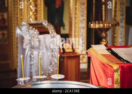 Christening in the church, candles at children baptismal font. Details in the orthodox christian church Stock Photo
