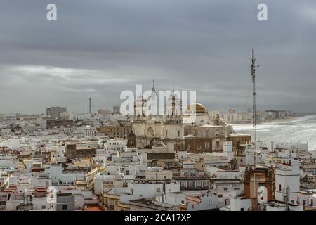 Aerial dramatic panoramic view of the old city, rooftops and Cathedral de Santa Cruz in cloudy day from tower Tavira in Cadiz, Andalusia, Spain.Europe Stock Photo