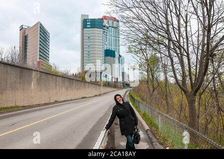 Niagara Falls, Canada - APRIL 25, 2012: Happy woman at the foot of the Embassy Suites hotel in Niagara Falls during the cloudy day. Stock Photo