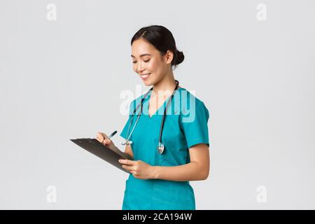 Healthcare workers, preventing virus, quarantine campaign concept. Beautiful smiling asian doctor, nurse running checkup in hospital, looking at Stock Photo