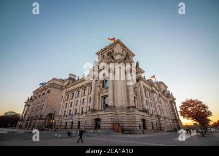 German Reichstag, the German parliament building in Berlin at sunset. Some german flags and one European waving. Politics and architecture concepts. Stock Photo