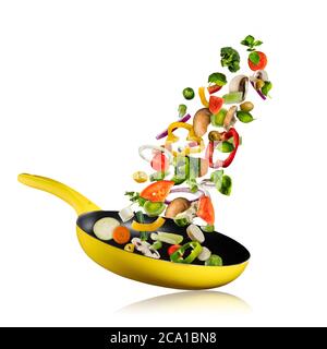 Fresh vegetables flying into a pan, isolated on white background. Concept of flying food, preparation, diet and healthy eating. Stock Photo