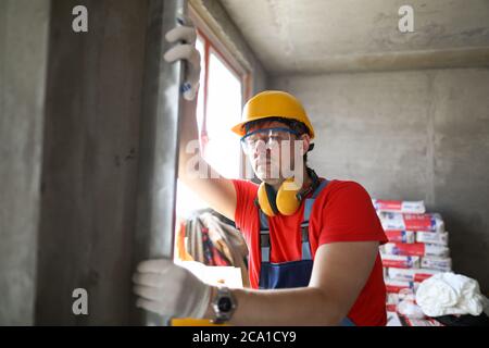 Builder measures level wall at construction site Stock Photo