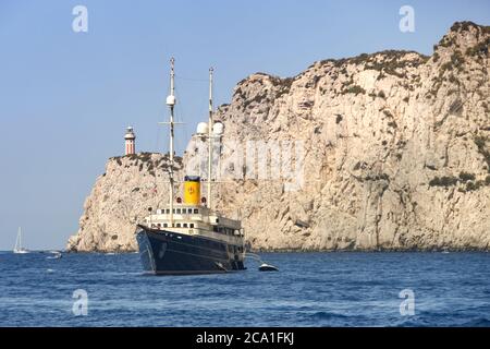 ISLE OF CAPRI, ITALY - AUGUST 2019: Luxury superyacht at anchor near the Punta Carena lighthouse on the Isle of Capri.