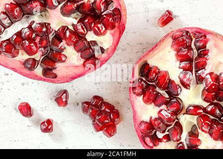 Pomegranate halves, gem like fruits scattered on white board, photo from above. Stock Photo