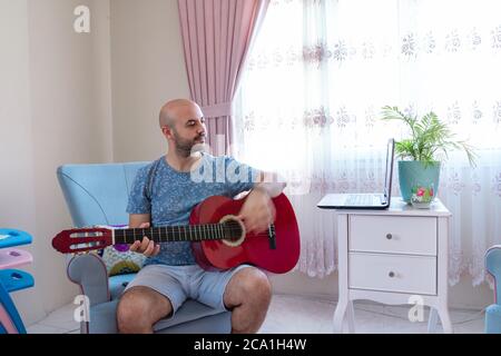 Teenager holding guitar with online conversation. Stock Photo