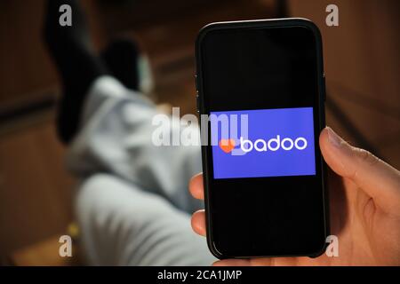 Badoo application on the smartphone in mans hand. Man laying and using application for dating and meeting. Social network concept, July 2020, Prague Stock Photo