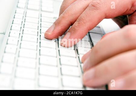 male hands typing keys on a white computer keyboard in an office. Technology and work. Stock Photo