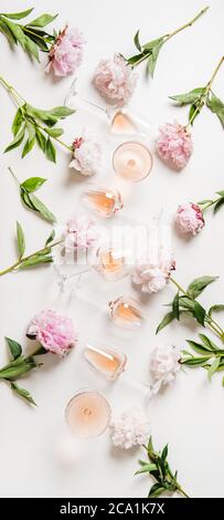 Rose wine in glasses and peony flowers over white background Stock Photo