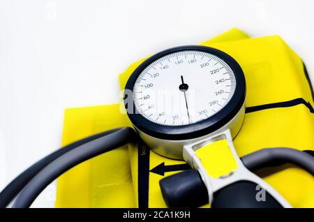 a portable sphygmomanometer resting on a yellow cuff for adults. Instrument for measuring blood pressure. Graduated scale with pressure indicator. Med Stock Photo