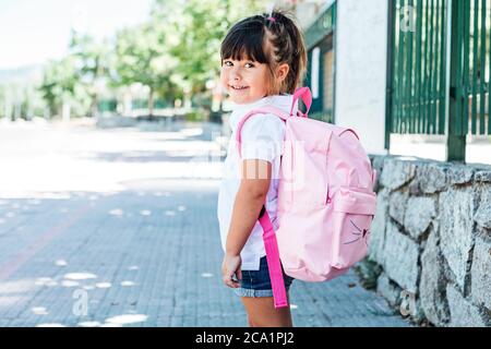 Black-haired girl wearing a pink backpack goes to school. School concept Stock Photo