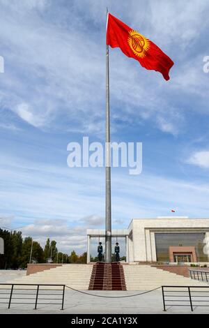 Kyrgyzstan flag pole guarded by two guard of honor in Ala Too Square in Bishkek with Kyrgyz Historical Museum behind. Stock Photo