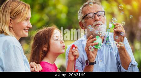 Happy family blowing soap bubbles in the park. Stock Photo