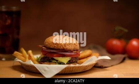 Close up view of fresh tasty grilled burger and french fries serving on wicker tray Stock Photo