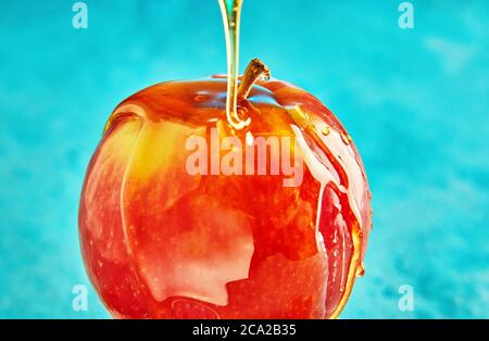 Rosh hashanah - jewish New Year holiday concept. Honey flows down an apple on a blue background.
