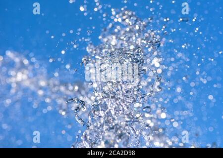 Water droplets spraying from a fountain in abstract design on blue sky background and detail and contrast. Concept. Stock Photo