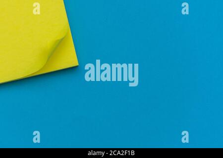 Bright yellow posted note on bright blue flat lay background for education or business organization and reminder concepts. Stock Photo
