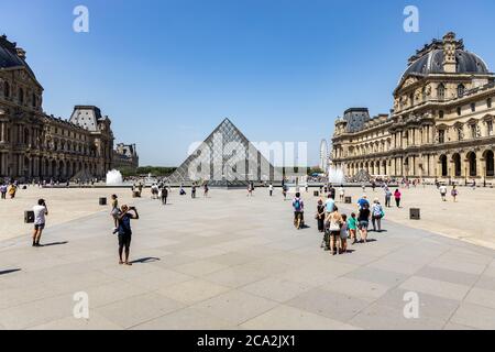 Paris, France - June 27, 2019: View of pyramid and fountain at courtyard of Louvre Museum. Louvre Museum is one of the largest and most visited Stock Photo