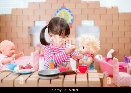 young girl pretend play babysitting with baby doll at home Stock Photo