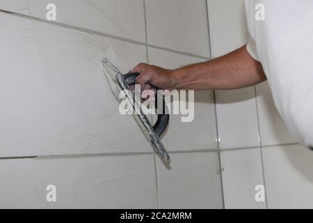 Tiler laying wall tiles in a bathroom Stock Photo