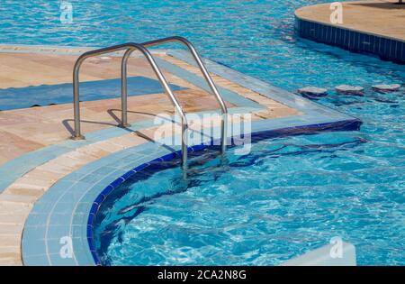 metal descent into pool with blue water Stock Photo