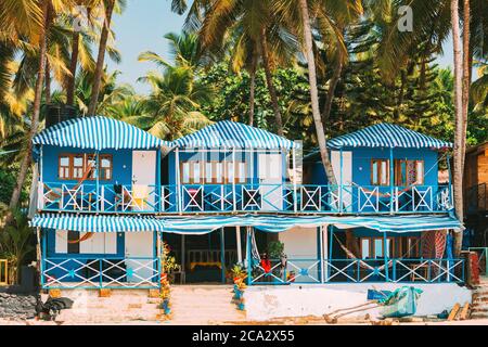 Canacona, Goa, India. Famous Painted Guest Houses On Palolem Beach Against Background Of Tall Palm Trees In Sunny Day.