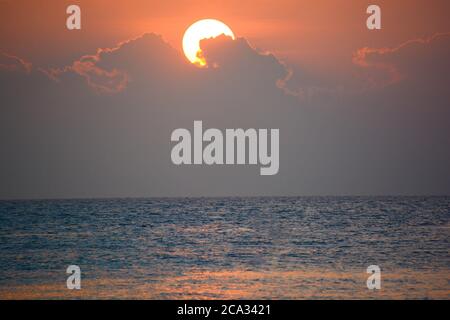 sunset after a monsoon rain that creates steam from the sea with ...