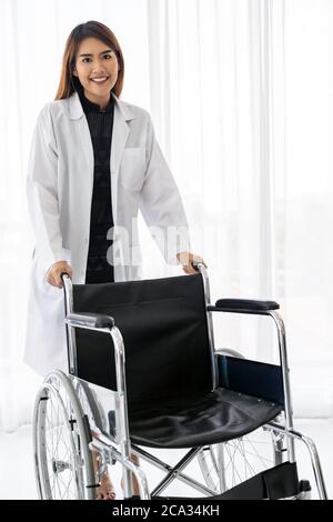 Portrait of confident female doctor medical professional holding wheelchair examination room in hospital clinic.