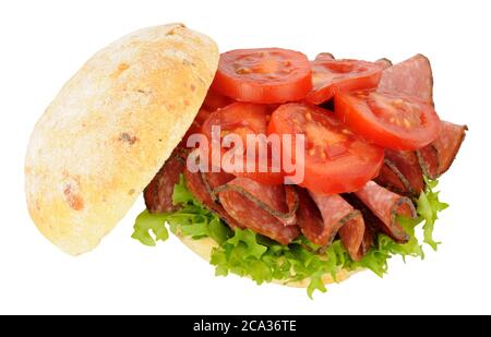 Spicy salami and tomato sandwich in a crusty bread roll isolated on a white background Stock Photo