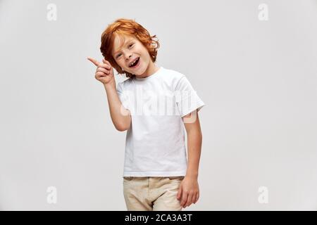 Cheerful red-haired boy points his finger towards Copy Space Stock Photo