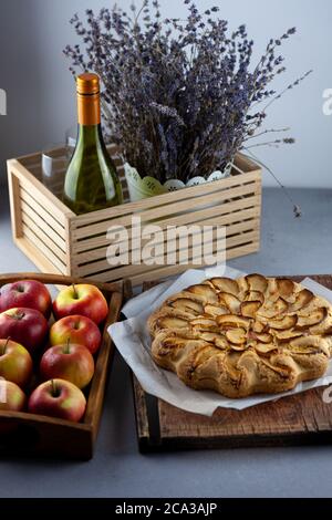 Apple pie and apples. Round homemade cake. Simple pastry made from shortcrust pastry and caramelized apple. Sweet pastries. Still life with lavender Stock Photo