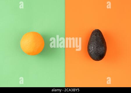 Avocado and orange on colorful background. Pop art design, creative summer food concept. Stock Photo