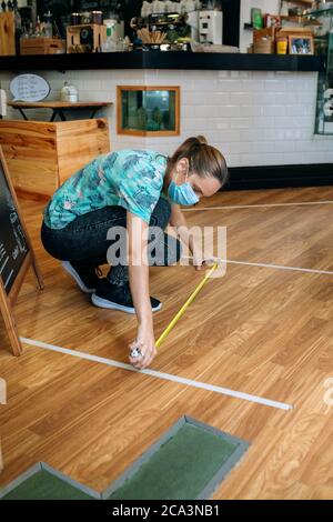 Coffee shop worker measuring floor marks Stock Photo