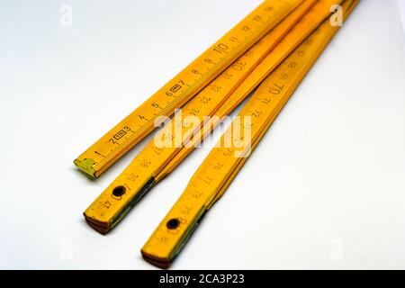 Yellow wooden folding meterstick with brass ends isolated on a white background. Fully extended it measures 2 meters. Measuring instrument used in con Stock Photo