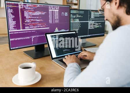 Cropped image of programmer man typing on keyboard while working with computers in office Stock Photo
