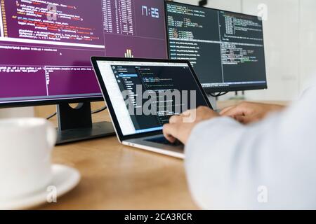 Cropped image of programmer man typing on keyboard while working with computers in office Stock Photo