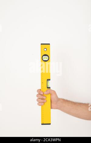Close-up of unrecognizable repairman holding yellow construction level against isolated background Stock Photo