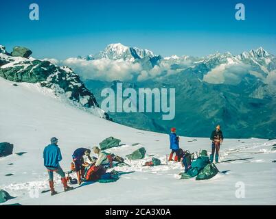 Switzerland Arolla. These are the mountains of the Arolla Alps in Switzerland that are seen and crossed on the old hunters high mountain trade route between the French town of Chamonix and the Swiss town of Zermatt. Climbers take a break in the area known as the Plateau du Couloir on the Col du Sonadon a large flat glacial area at the foot of the Grand Combin mountain with excellent mountain scenery looking towards Mont Blanc Stock Photo