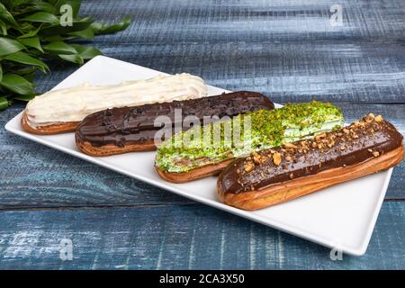 Tasty chocolate eclair cakes with leaves on the blue background Stock Photo