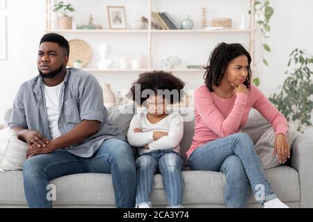 Family Misunderstanding. Black Parents And Little Daughter Ignoring Each Other After Argue Stock Photo