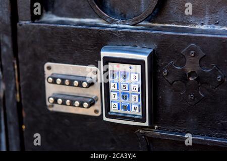 combination lock on a black iron gate with electronic buttons and old mechanical, close-up. Stock Photo