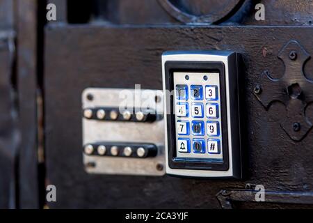 combination lock on a black iron gate with electronic buttons and old mechanical, closeup. Stock Photo