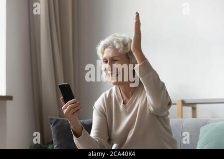 Grandmother holding smartphone feels happy by great news in sms Stock Photo